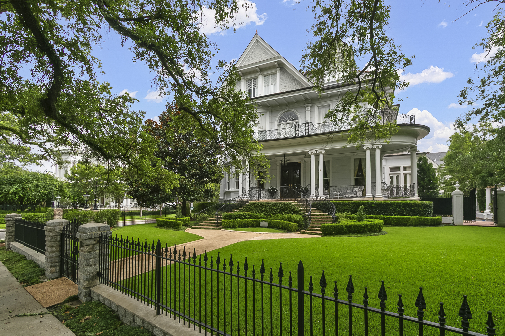 A white columned historic mansion with wrought-iron galleries in the Garden District of New Orleans